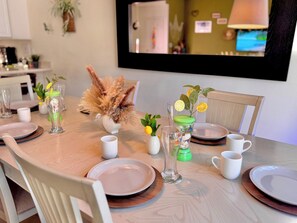 A dining table set with plates, cups, and a vase with dried flowers.