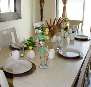 A dining table set with plates, glasses, and a centerpiece with dried plants and lemons.