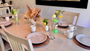 A dining table set with plates, cups, and a vase with dried plants.