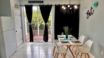 Un coin repas avec une table dressée pour deux personnes, un réfrigérateur et un panneau affichant des phrases positives.