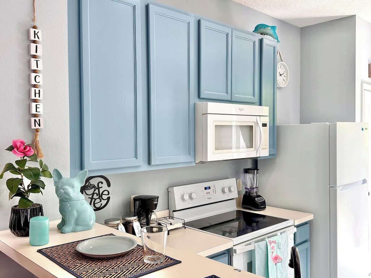 Une cuisine avec des armoires bleues, un réfrigérateur blanc, un four à micro-ondes et une cuisinière.