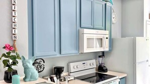 A kitchen with blue cabinets, a white refrigerator, a microwave, and a stove. - Level Up Your Vacation! Stylish Home Near Disney (Kissimmee)