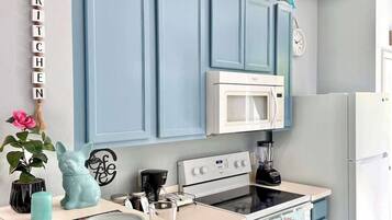 Une cuisine avec des armoires bleues, un réfrigérateur blanc, un four à micro-ondes et une cuisinière.