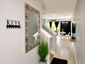 A hallway with a mirror, a plant, and a sign that reads 'KEYS'.
