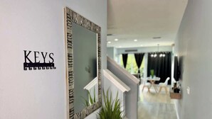 A hallway with a mirror and a sign that reads "KEYS". - Level Up Your Vacation! Stylish Home Near Disney (Kissimmee)