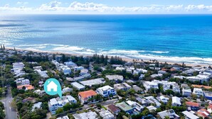 Vue aérienne d’une zone résidentielle côtière, avec des maisons, des routes et une plage.