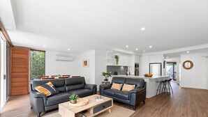 Un salon moderne avec deux canapés en cuir noir, une table basse en bois et un coin repas avec des chaises en bois.
