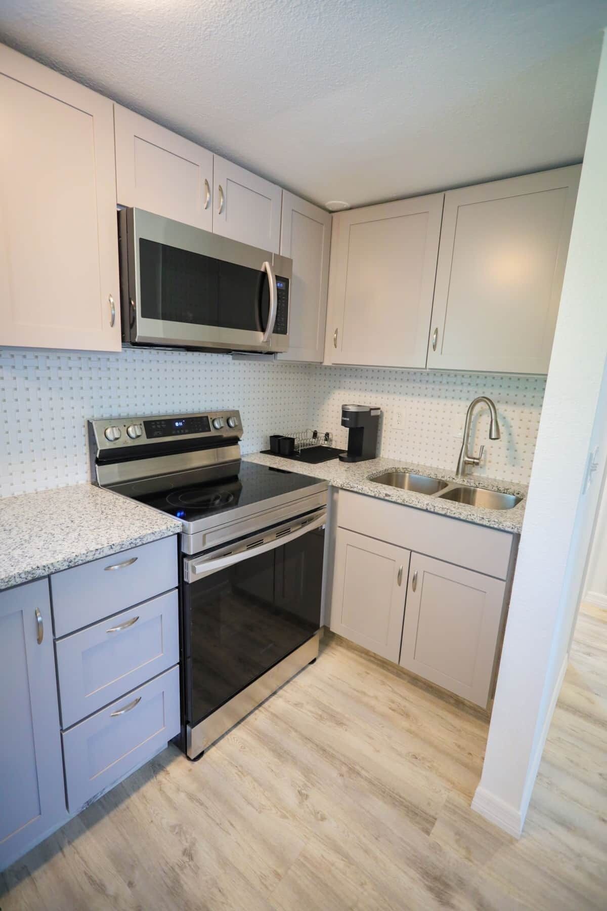 A compact kitchen with a microwave, stove, oven, and sink.