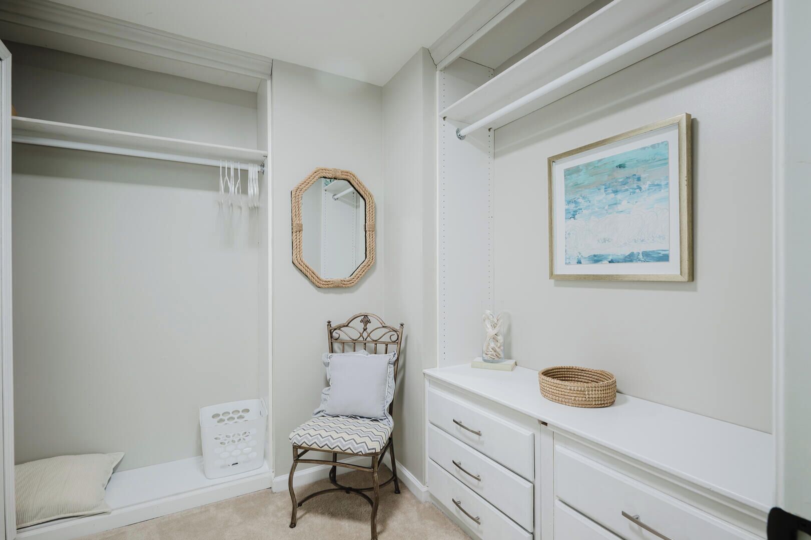 A walk-in closet with a bed, a chair, and a dresser.