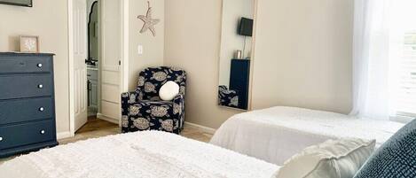 Une chambre avec deux lits, une commode, une chaise, un miroir et une décoration en forme d’étoile sur le mur.