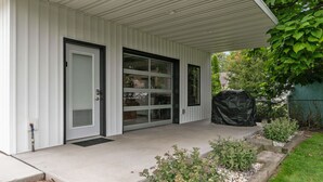 Une véranda couverte avec une porte-fenêtre coulissante et un espace barbecue abrité.