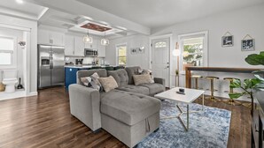 Un salon moderne avec un canapé d’angle gris, une petite table blanche et un tapis bleu.
