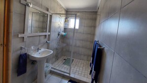 A bathroom with a sink, mirror, and shower. - Spacious cosy, self- Catering loft with own entrance in safe & secure area. (Swakopmund)