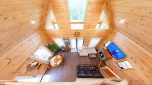 A wooden cabin interior with a dining area, seating, and a television.