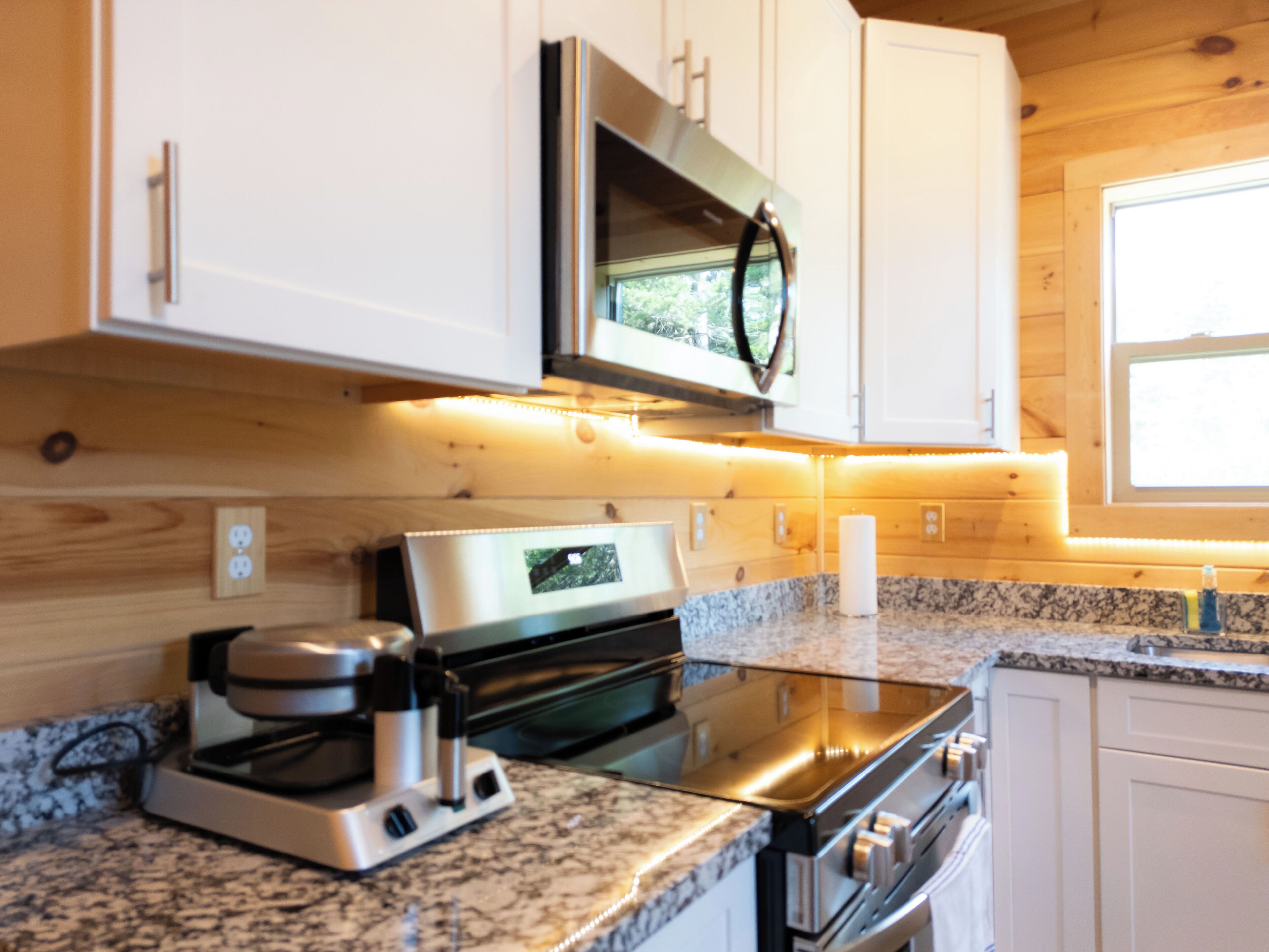 A kitchen with white cabinets, a stainless steel microwave, a coffee maker, and granite countertops.