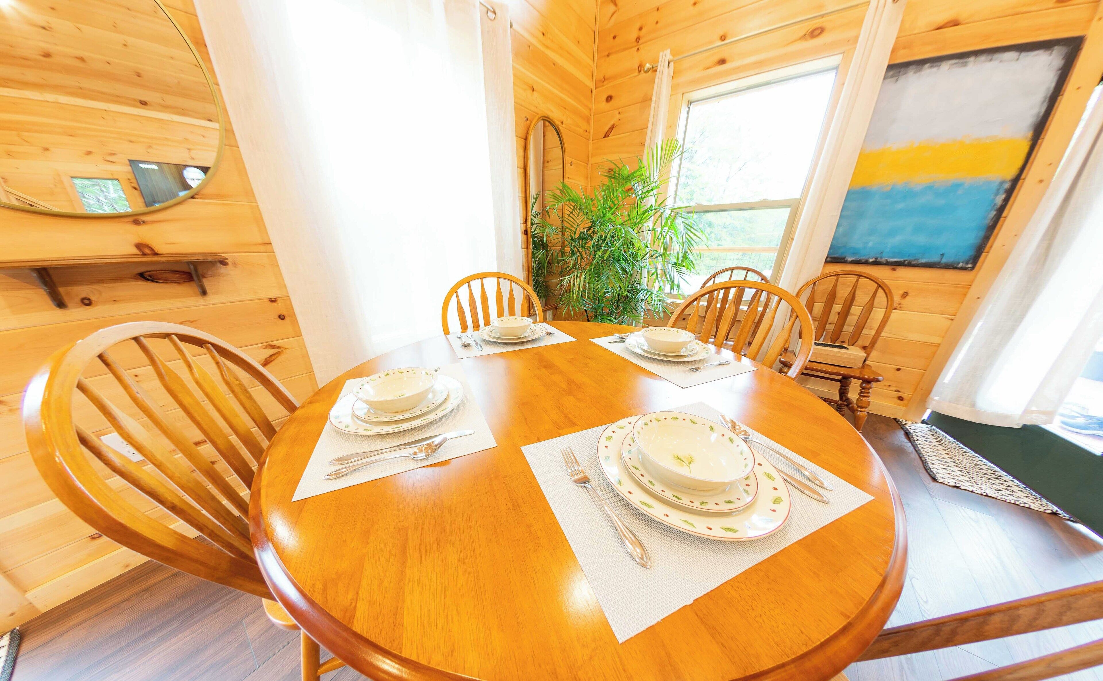 Comedor de madera con una mesa redonda dispuesta para cuatro personas, rodeada de sillas de madera.