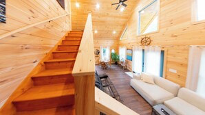 Un interior de madera con una escalera que conduce a un comedor y un sofá blanco.