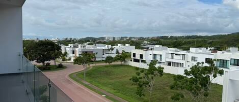 A modern residential area with white buildings, a green park, and a clear sky.