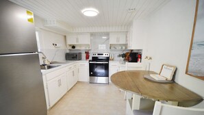 Una cocina moderna con armarios blancos, electrodomésticos de acero inoxidable y una mesa de comedor de madera.
