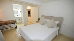 Un dormitorio con cama, mesita de noche y escritorio con silla.