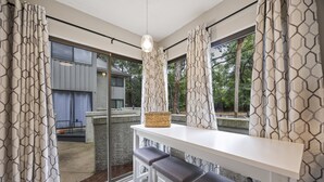 Una cocina moderna con encimera blanca, tres taburetes de bar y una lámpara colgante.