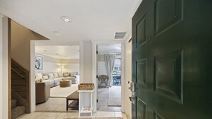 Un pasillo que conduce a una sala de estar con un sofá, una mesita y una cesta.