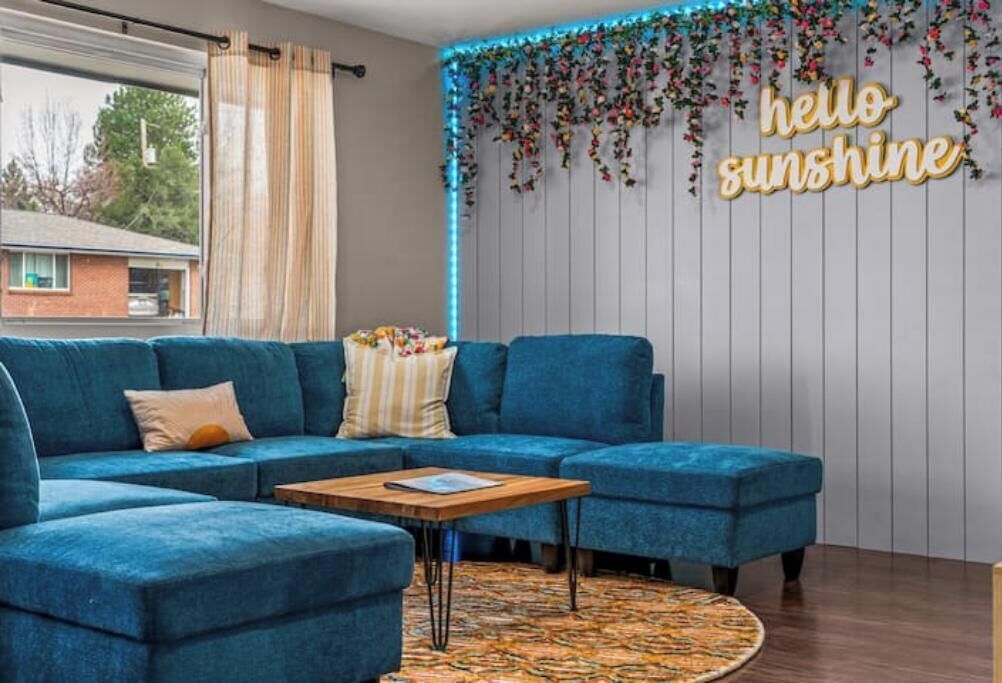 Een moderne woonkamer met een blauwe modulaire bank, een klein houten bijzettafeltje en een kamerbreed tapijt met een patroon.