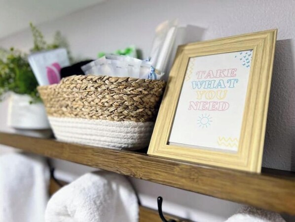 A shelf with a woven basket containing toiletries, a framed inspirational quote, and a potted plant.