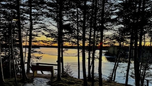 A bench overlooking a frozen lake with a forested backdrop. - Welcome to Sunset Cove, Cozy home, enjoy the landscaped property & outdoor area. (Goobies)
