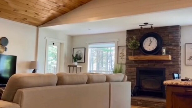 A living room with a stone fireplace, a sofa, and a television. - Welcome to Sunset Cove, Cozy home, enjoy the landscaped property & outdoor area. (Goobies)