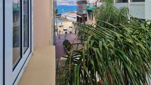 Blick vom Balkon auf eine Küstenlandschaft mit Gebäuden, einem Strand und Booten.