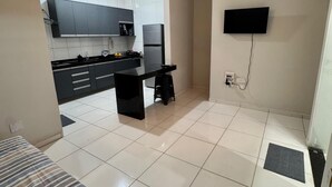 Une cuisine de taille réduite, avec des carreaux blancs, un plan de travail noir et un ventilateur de plafond.