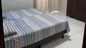Une chambre à coucher avec un lit, un climatiseur, une armoire et une fenêtre avec des rideaux.
