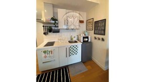 A compact kitchen with white cabinets, a microwave, and a sink. There is a decorative plant on the countertop and a framed picture on the wall. - Acqua Private Residences - Ethereal Suite Room 1 (Makati City)