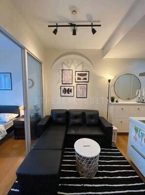 A modern bedroom with a sofa bed, a round coffee table, and a striped rug.