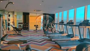 A modern gym with treadmills, weight machines, and a colorful zigzag carpet. - Acqua Private Residences - Ethereal Suite Room 1 (Makati City)