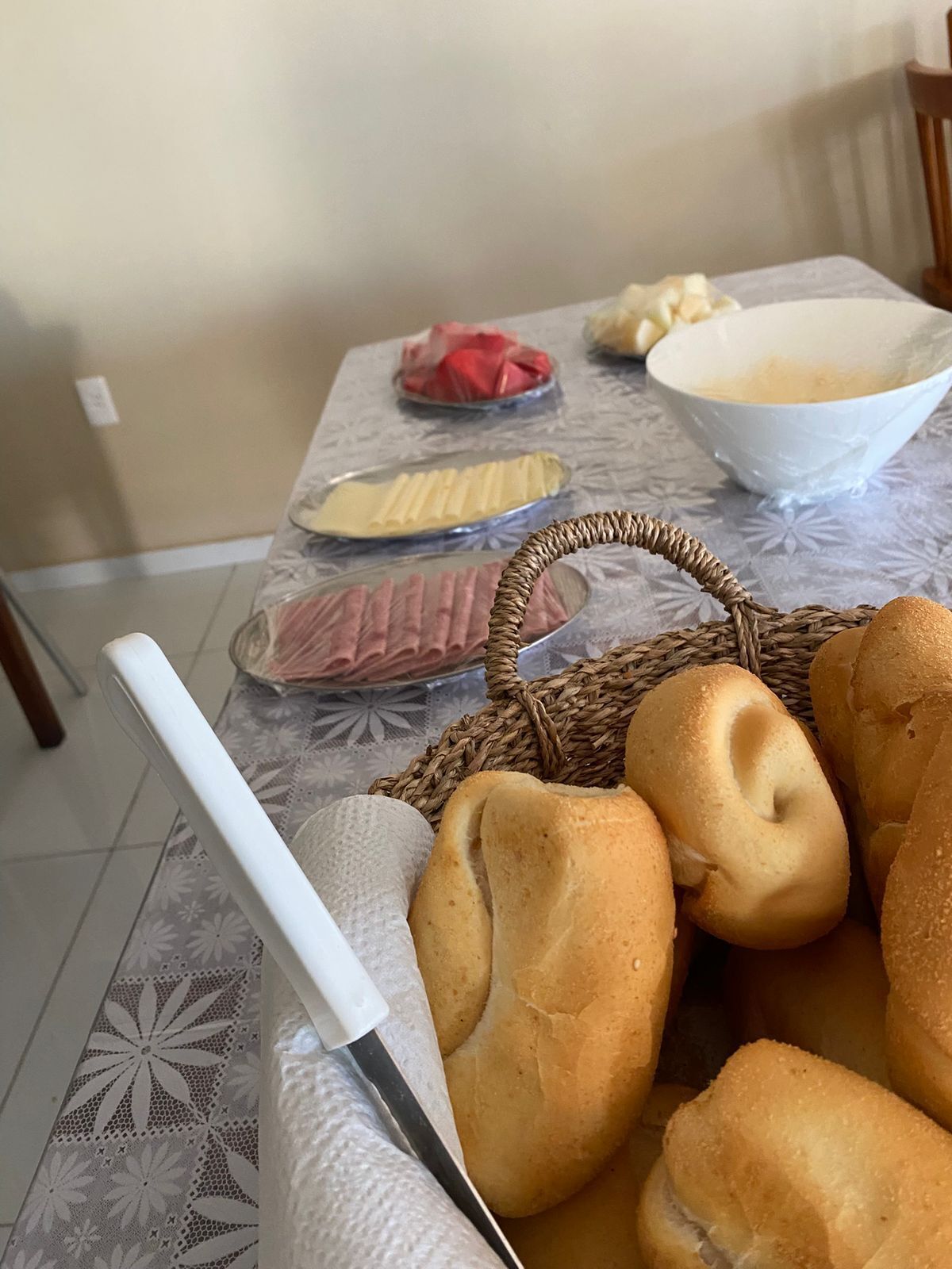 Un tavolo con diversi cibi, tra cui pane, un coltello e una ciotola.