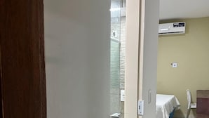 A hotel room with a bed, a small table, and a chair. There is a window with a view of the outside. - Pousada Toco do Mar (Fortaleza)