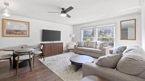 A modern living room with a dining area, a sofa set, a TV, and a ceiling fan. - The Alpine Estate At Copper Chase (Brian Head)