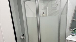 A bathroom with a glass-enclosed shower, a toilet, and a sink with a countertop. - Beautiful apartment on Richmond near via rail (London)