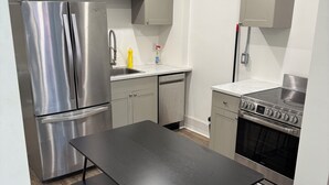 A modern kitchen with stainless steel appliances, a wooden floor, and a black dining table. - Beautiful apartment on Richmond near via rail (London)