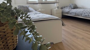 A bedroom with a bed, bedside tables, a window, and a plant. - Fitters' and vacation apartment near Heidelberg in the Odenwald with balcony & garden (Wilhelmsfeld)