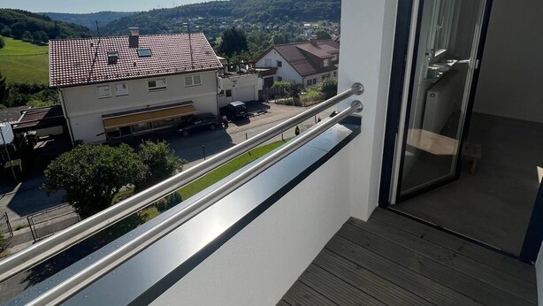 A balcony with a view of a residential area, including houses and a road. - Fitters' and vacation apartment near Heidelberg in the Odenwald with balcony & garden (Wilhelmsfeld)