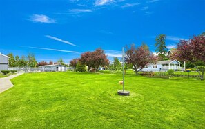A well-maintained lawn with a flagpole and a small flag, surrounded by houses and trees. - Beach View Condo in Birch Bay WA (Blaine)