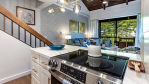 Una cocina moderna con estufa integrada, una escalera de madera y un ventanal con vistas al exterior.