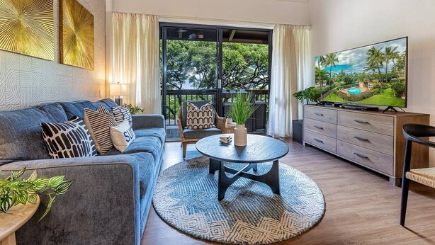 Una sala de estar moderna con un sofá, una mesa de centro y un televisor sobre un mueble de madera.