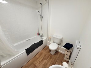 Ein Badezimmer mit Badewanne, Toilette und Heizkörper.