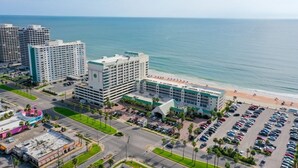 A hotel with a beach view, multiple parking lots, and a large building with a prominent sign.