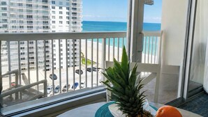 A balcony with a view of the ocean and a parking lot.