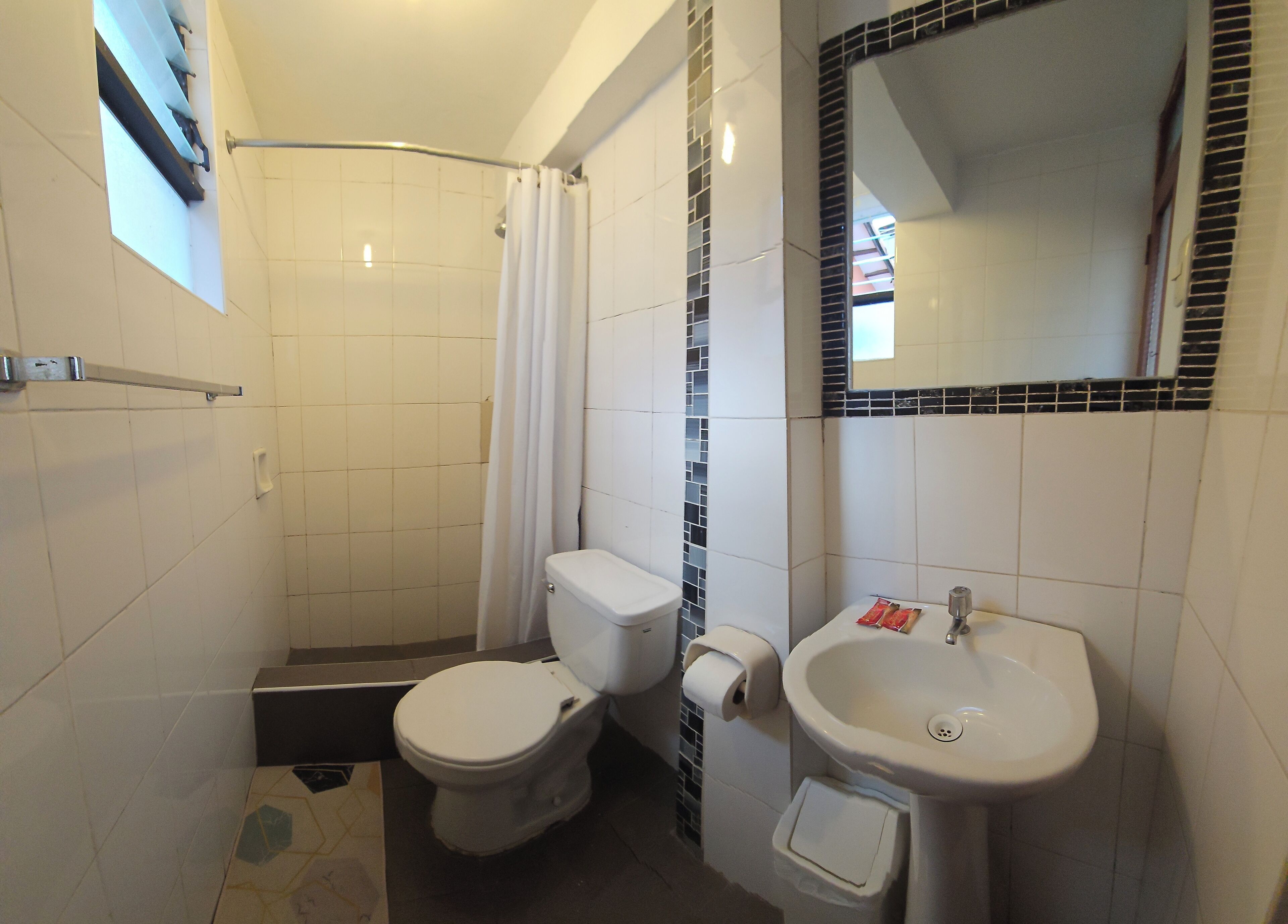 Une salle de bain équipée d’une douche, de toilettes, d’un lavabo et d’un miroir.